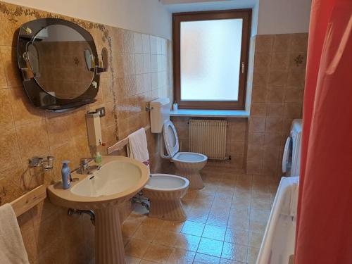 uma casa de banho com 2 WC, um lavatório e um espelho. em casetta in montagna em Mocenigo