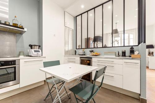 une cuisine avec des armoires blanches et une table et des chaises dans l'établissement École Militaire, à Paris