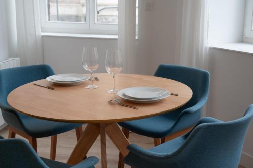 - une table en bois avec 2 verres à vin et des chaises bleues dans l'établissement One bedroom apartment with parking, city center, à Tourcoing