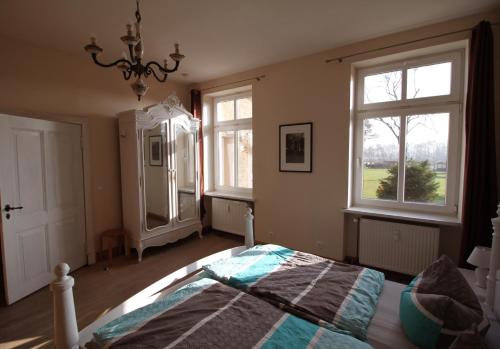a bedroom with a bed and two windows at Ferienwohnung im Gutshaus Mühlhof in Prenzlau