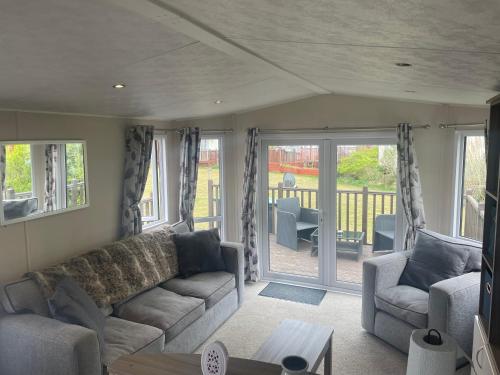 a living room with a couch and chairs and sliding glass doors at Beautiful caravan on Billing Aquadrome in Northampton