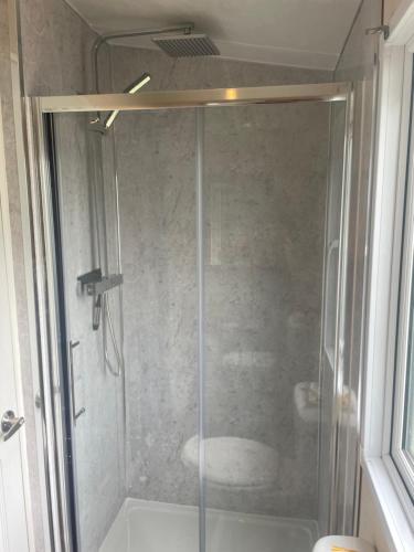 a shower with a glass door in a bathroom at Beautiful caravan on Billing Aquadrome in Northampton