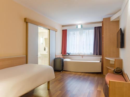 シュトゥットガルトにあるイビス シュトゥットガルト セントラムのベッドとバスタブ付きのホテルルームです。