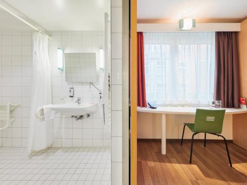 a bathroom with a sink and a shower and a green chair at ibis Stuttgart Centrum in Stuttgart