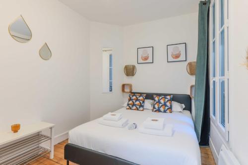 Schlafzimmer mit einem Bett mit weißer Bettwäsche und einem Schreibtisch in der Unterkunft Cozy Parisian Retreat in the Heart of the City in Paris