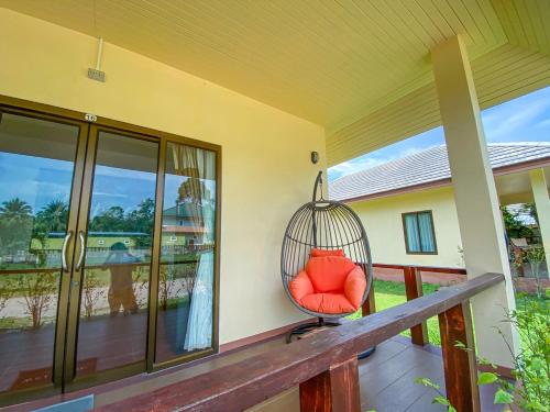 a swing sitting on the porch of a house at Chaithalay Khanom Resort in Ban Phang Phrao