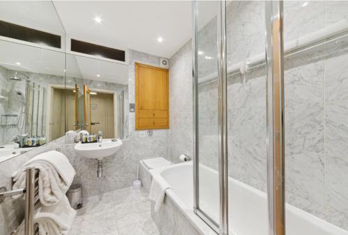 La salle de bains est pourvue d'une baignoire et d'un lavabo. dans l'établissement Nell Gwynn Chelsea Accommodation, à Londres