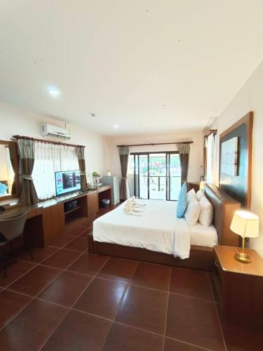 a bedroom with a bed and a desk and a television at Chaithalay Khanom Resort in Ban Phang Phrao