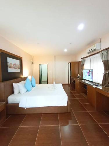a bedroom with a white bed and a television at Chaithalay Khanom Resort in Ban Phang Phrao