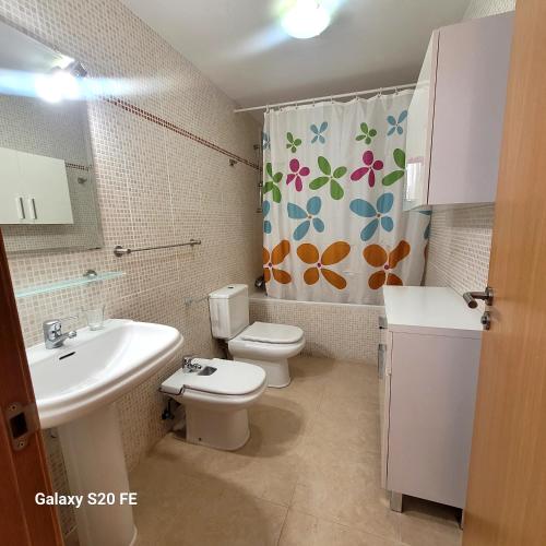 a bathroom with a sink and a toilet and a shower curtain at apartamento llandells casa kiko in Peniscola