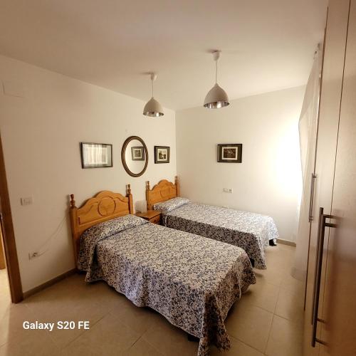 1 dormitorio con 2 camas y espejo en apartamento llandells casa kiko, en Peñíscola