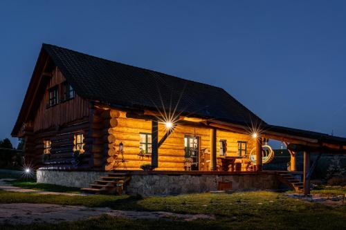 a log cabin with lights on it at night at Srub Pohodář v Novohradských horách in Benešov nad Černou