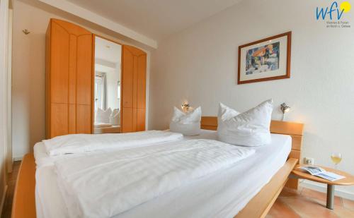 1 dormitorio con 1 cama grande con sábanas y almohadas blancas en Ferienpark Seedorf Haus Granitz - Ferienwohnung 2, en Sellin