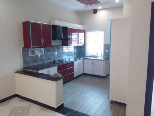 a kitchen with white counters and red cabinets at Edge of Islamabad Entrance in Islamabad