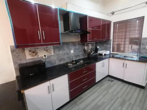 a kitchen with red cabinets and white counters at Edge of Islamabad Entrance in Islamabad