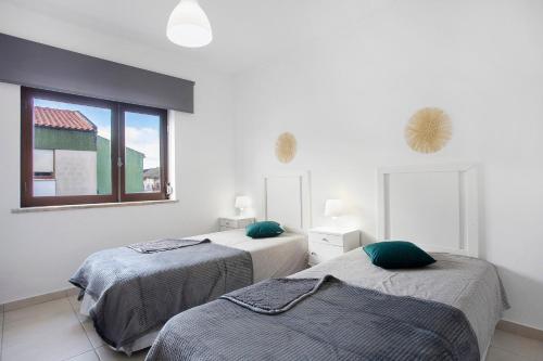 zwei Betten in einem weißen Zimmer mit Fenster in der Unterkunft A O - Augusta in Peniche