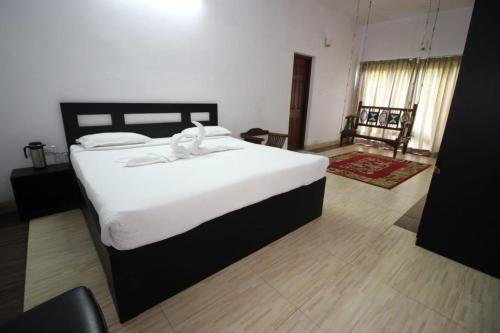 a bedroom with a large bed with white sheets at Mount n Mist in Ooty