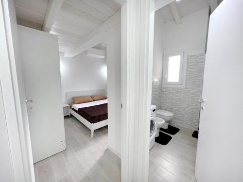 een witte kamer met een bed en een toilet bij Affittimoderni Castelsardo Il Sole - CSSO11 in Castelsardo