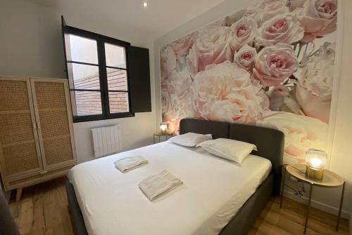Cocon des Chandeliers في بوردو: غرفة نوم مع سرير كبير مع ورود وردية على الحائط