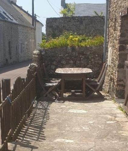 une table de pique-nique assise à côté d'un mur de pierre dans l'établissement Maison en pierres à 1200m de la mer, à Agon-Coutainville
