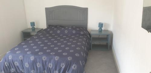 - une chambre avec un lit doté d'une couverture bleue et de 2 tables de chevet dans l'établissement Maison en pierres à 1200m de la mer, à Agon-Coutainville