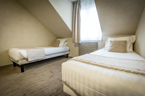 a bedroom with two beds and a window at Hôtel De Brunville & Spa in Bayeux