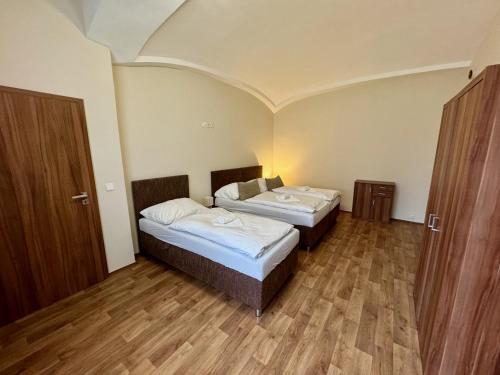 two beds in a small room with wooden floors at Apartmány Laubeho náměstí in Teplice