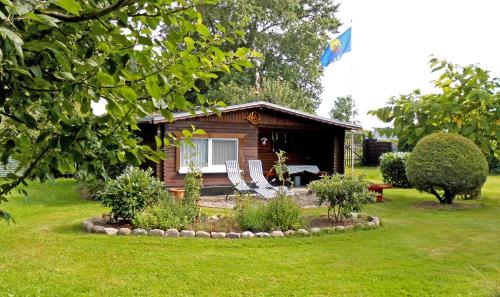 eine kleine Hütte mit Stühlen davor in der Unterkunft Bungalow und Ferienwohnung auf Rügen in Kluis