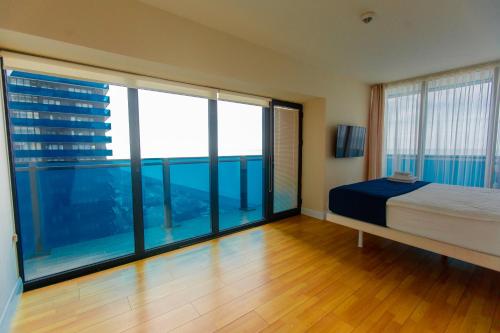 Welcome To Batumi في باتومي: غرفة نوم بسرير ونوافذ زجاجية كبيرة