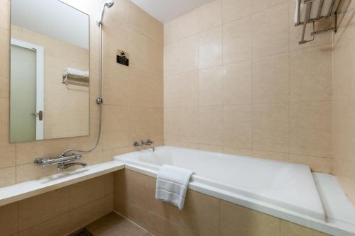 a bathroom with a tub and a sink and a mirror at Belgravia Serviced Residence Wuxi in Wuxi