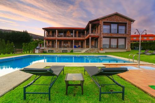 波伊奧的住宿－阿馬奎亞酒店，一座房子前面设有游泳池和两把椅子