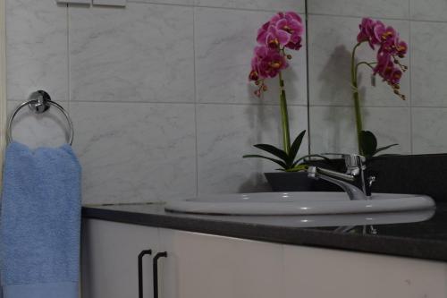 a bathroom with a sink and purple flowers on a counter at MAMA'S FLAT - ΤΟ ΔΙΑΜΕΡΙΣΜΑ ΤΗΣ ΜΑΜΑΣ in Strovolos