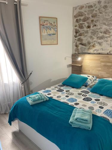 een slaapkamer met een bed met blauwe lakens en blauwe kussens bij Appartement La Tourraque côté mer in Antibes
