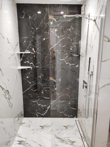 a bathroom with a shower with black and white marble at DiP HOME APARTMENTS in Pomorie