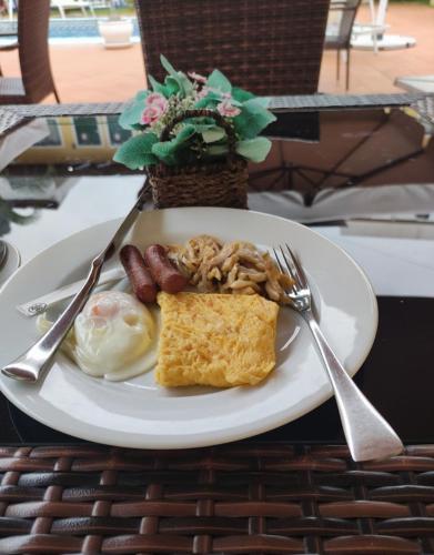 a plate of breakfast food with eggs sausage and toast at Fortaleza Guesthouse in Luanda