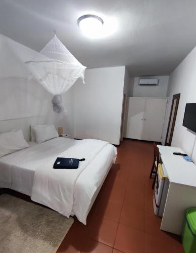 a bedroom with a white bed with a black tray on it at Fortaleza Guesthouse in Luanda