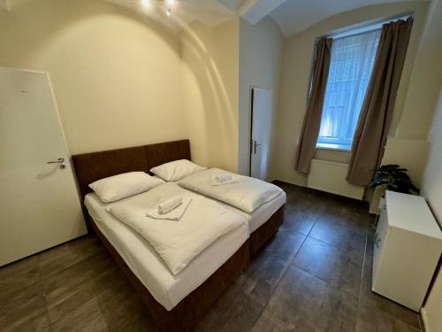 a bedroom with a bed with white sheets and a window at Apartmány Laubeho náměstí in Teplice