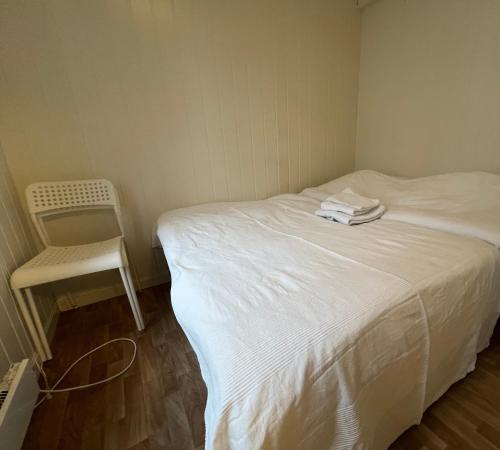 niewielka sypialnia z białym łóżkiem i krzesłem w obiekcie MyCondo no - Snorres Gt 4b apt 3 w mieście Tønsberg