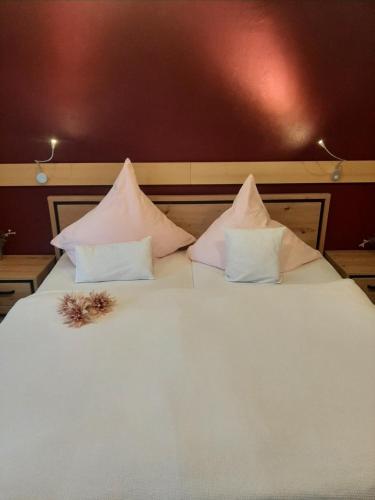 a white bed with four pillows and a flower on it at Fewo Zum Sonnenschein in Simmerath