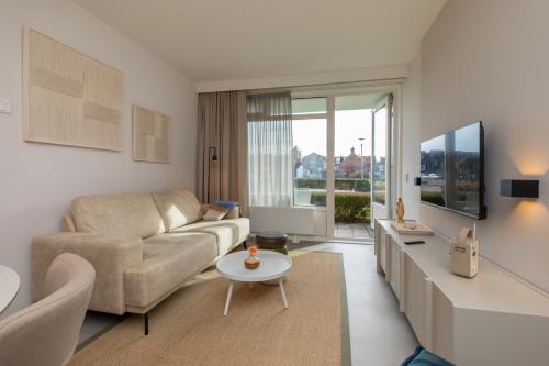 a living room with a couch and a table at Welcome in - Appartementen Kurhaus - Nieuwstraat 1 Zoutelande, nabij strand, terras, sauna in Zoutelande