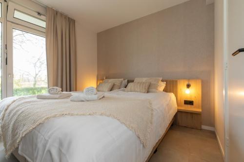 a bedroom with a bed with white sheets and a window at Appartement - Nieuwstraat 1 - Zoutelande 'Kurhaus - 2' in Zoutelande