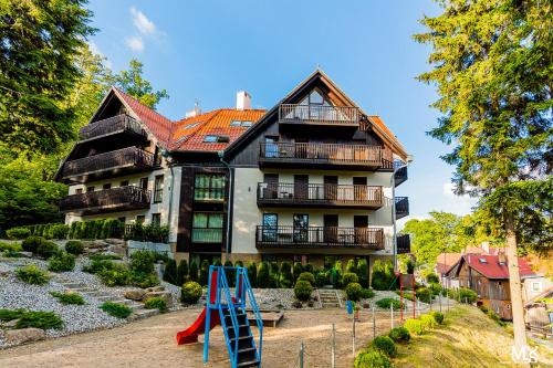 a large house with a playground in front of it at Apartamentowiec Panorama Gór City Center Family&Pet-friendly in Szklarska Poręba