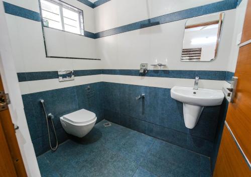 a blue and white bathroom with a toilet and a sink at Cool Nest 5 BR Pool Villa Munnar by VOYE HOMES in Munnar