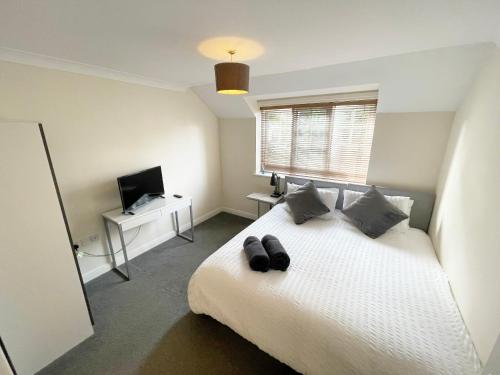 um quarto com uma cama branca com dois sapatos em Travaal.©om - 2 Bedroom Apartment - Farnborough em Farnborough