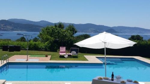 a swimming pool with an umbrella and a table and chair at A Maquia in Poio