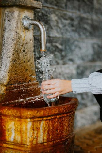 a person is drinking water from a rusty fountain at Hotel Tusnad in Băile Tuşnad