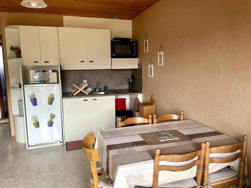 Appartement au pied des pistes في Les Fourgs: مطبخ مع طاولة وثلاجة