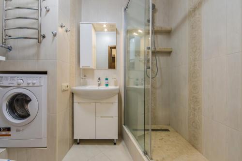 uma casa de banho com um lavatório e uma máquina de lavar roupa em Апартаменти в центрі з видом на костел em Kiev