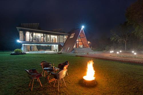 a fire pit in front of a building at night at ELIVAAS 3 BHK with Treehouse & Pvt Pool - Handa's Gateway in Dhauj