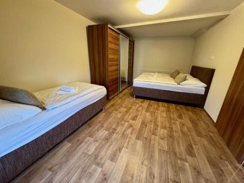 two beds in a room with wooden floors at Apartmány Laubeho náměstí in Teplice